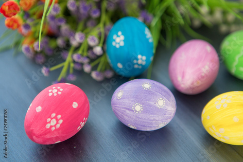 Easter eggs decoration with and flowers on gray wooden table.