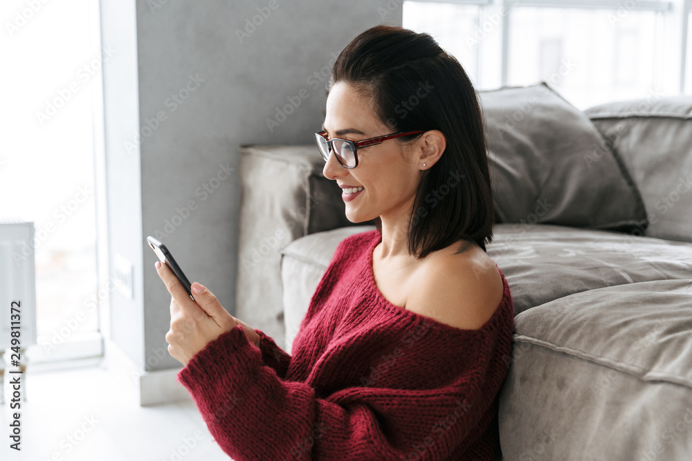 Beautiful woman indoors in home on sofa using mobile phone. Beautiful woman indoors in home on sofa using mobile phone.