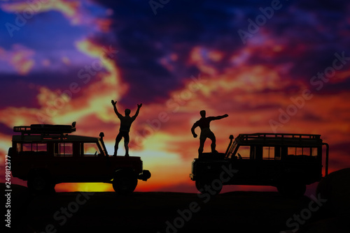 Miniature toys of two men celebrate triumphantly at the mountain concept at sunset or sunrise.