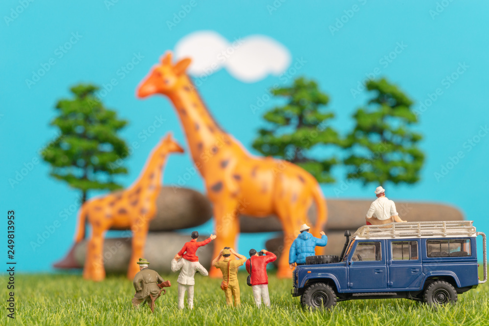 Miniature toys of a group of people on safari trip watching giraffes