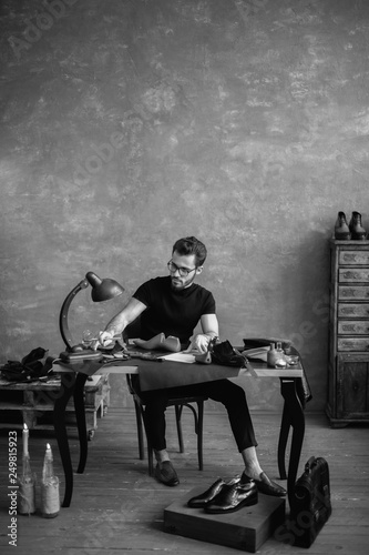 black and white photo. cute guy working with shoes, full length photo