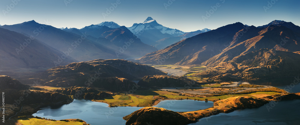 Obraz premium Panorama at sunset of Roys Peak between Wanaka and Queenstown with a lake and Mount Aspiring and cook of the new zealand alps on the background