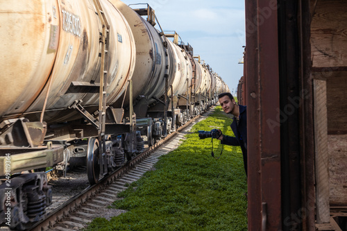 wagons transporting fuel or other industrial goods passing by abandoned wagons and a photographer choosing a moment to capture an image, making a shot of a scene
