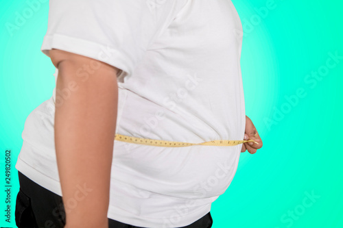 Unknown obese man measures his oversize belly