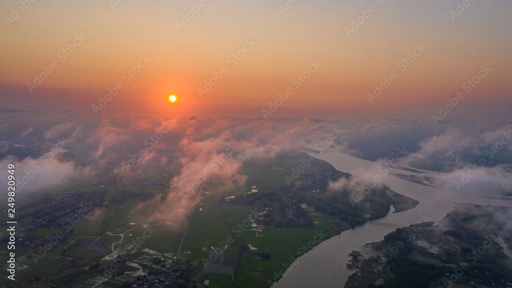 Arial drone shot of sunset in the sky above rice fields and river 