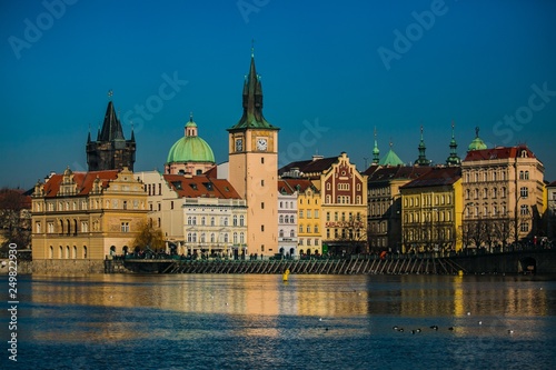 Prague, Czech Republic / Europe - February 16 2019: View of Novotneho footbridge and historical buildings, reflection in Moldau river, bright sunny cold day, blue sky, seagulls and ducks on water