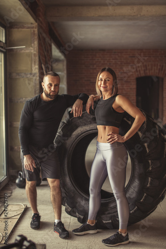 Healthy active couple of diverse caucasian sportspeople looking at camera while training in crossfit workout in gym. Sport and healthy lifestyle motivation.