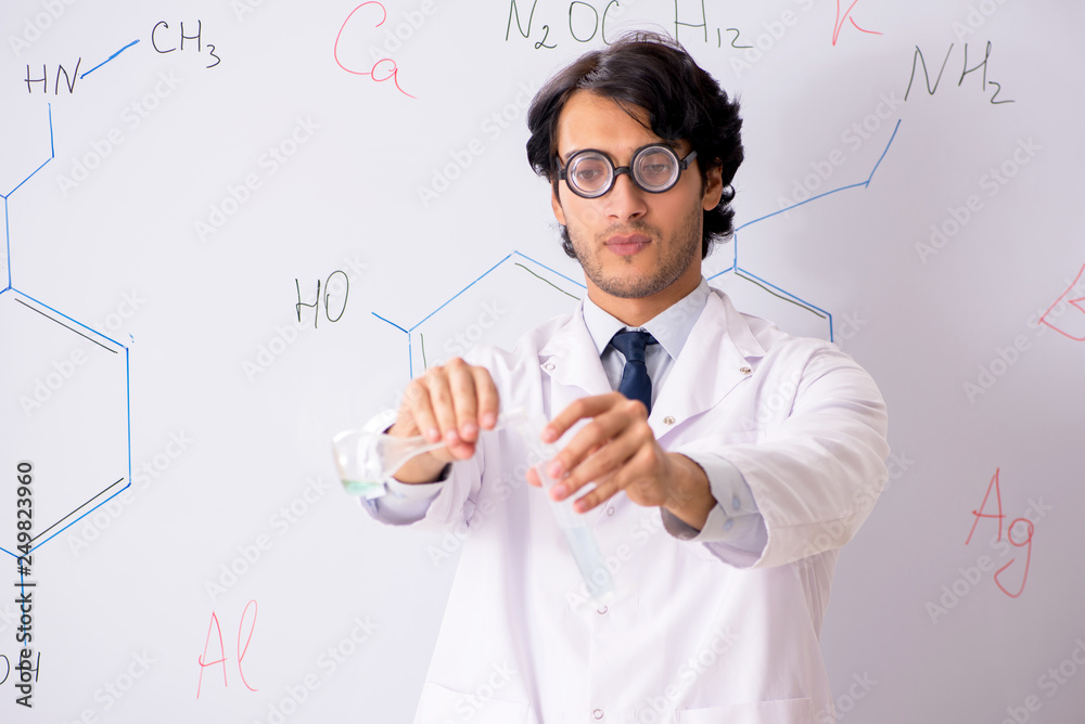 Young funny chemist in front of white board Young funny chemist in front of white board