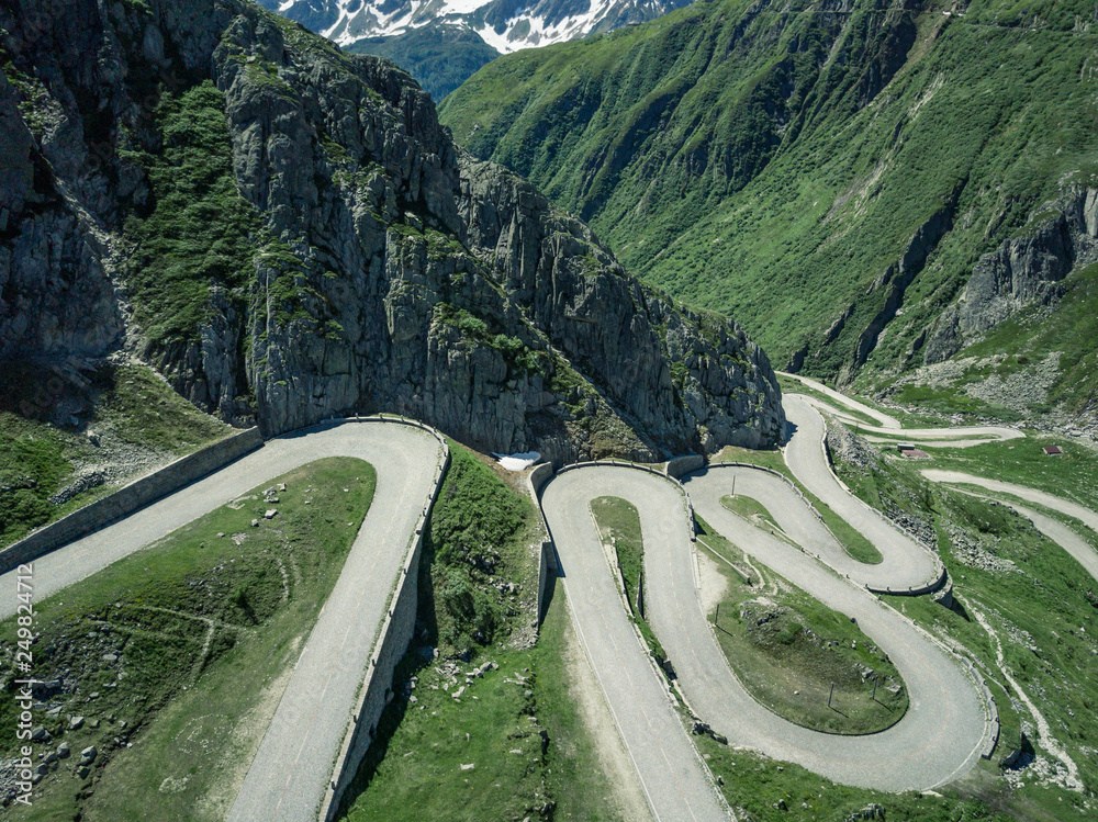 Drone shot of the upper section of Tremola Street at St Gotthard Pass. Green vegetation with many serpentines.