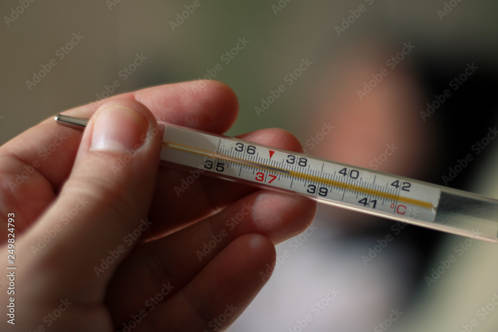An alcohol thermometer shows a temperature of 37.9 on a blurred