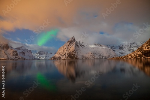 Aurora borealis dancing on mountain in fishing village at Reine and Sakrisoy, Lofoten, Norway Visiting the Lofoten Islands during winter time is a dream for all landscape photographers. 