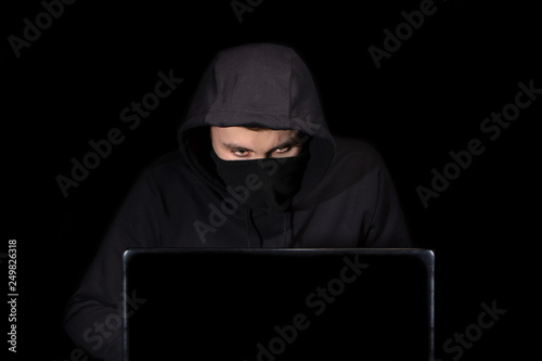Hacker with laptop initiating cyber attack, isolated on black