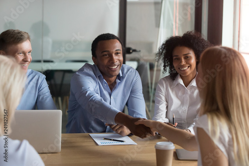 Black ceo handshaking with woman financier while sitting at meeting photo