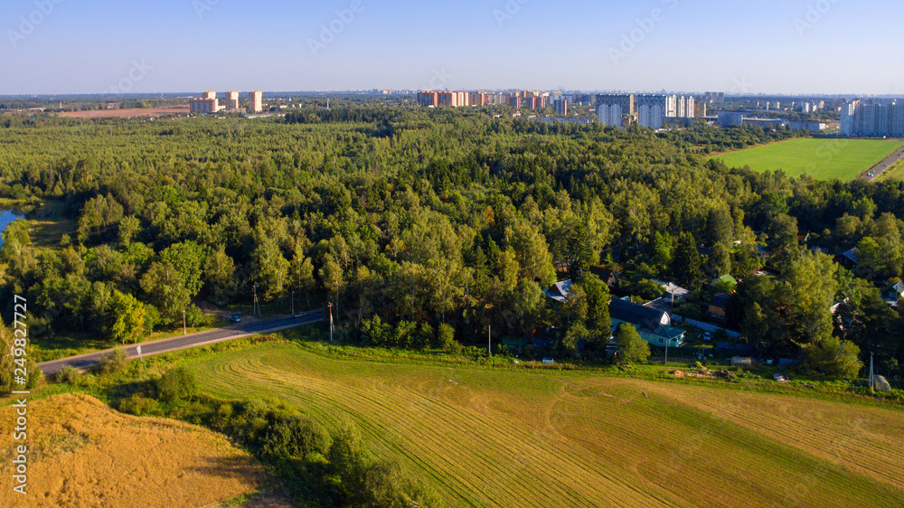 Top view of agricultural field, forest and residential area in the distance