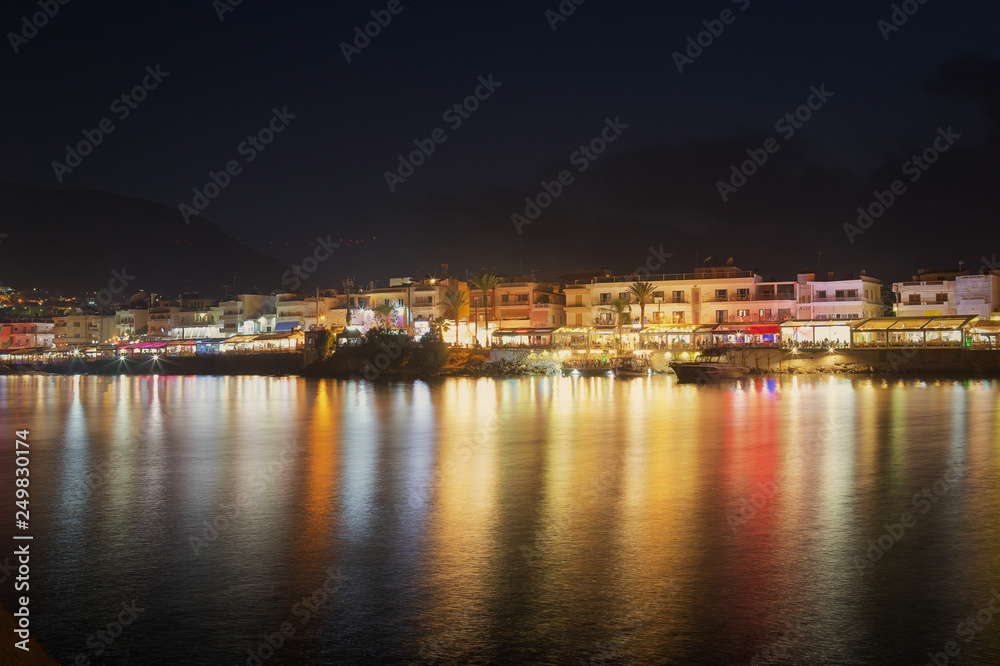 Night view of Hersonissos. Reflection of city lighting in the water.