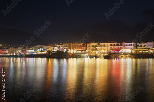 Night view of Hersonissos. Reflection of city lighting in the water. © Denis