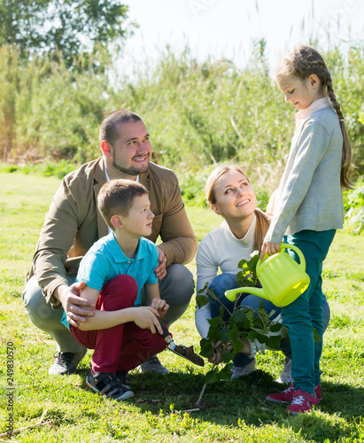 Happy family with two kids placing a new tree