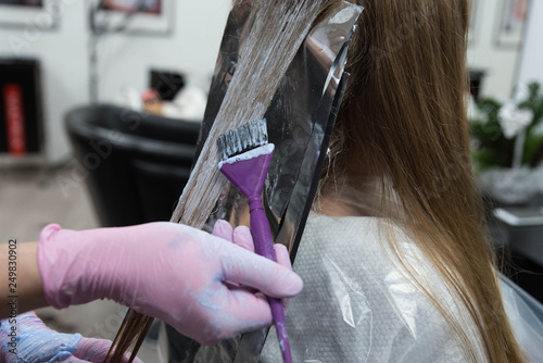 Professional hairdresser drying woman's hair with hairdryer in beauty salon