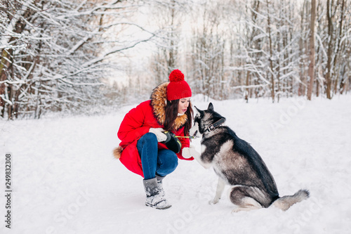 Woman caresses the Husky dog in winter forest