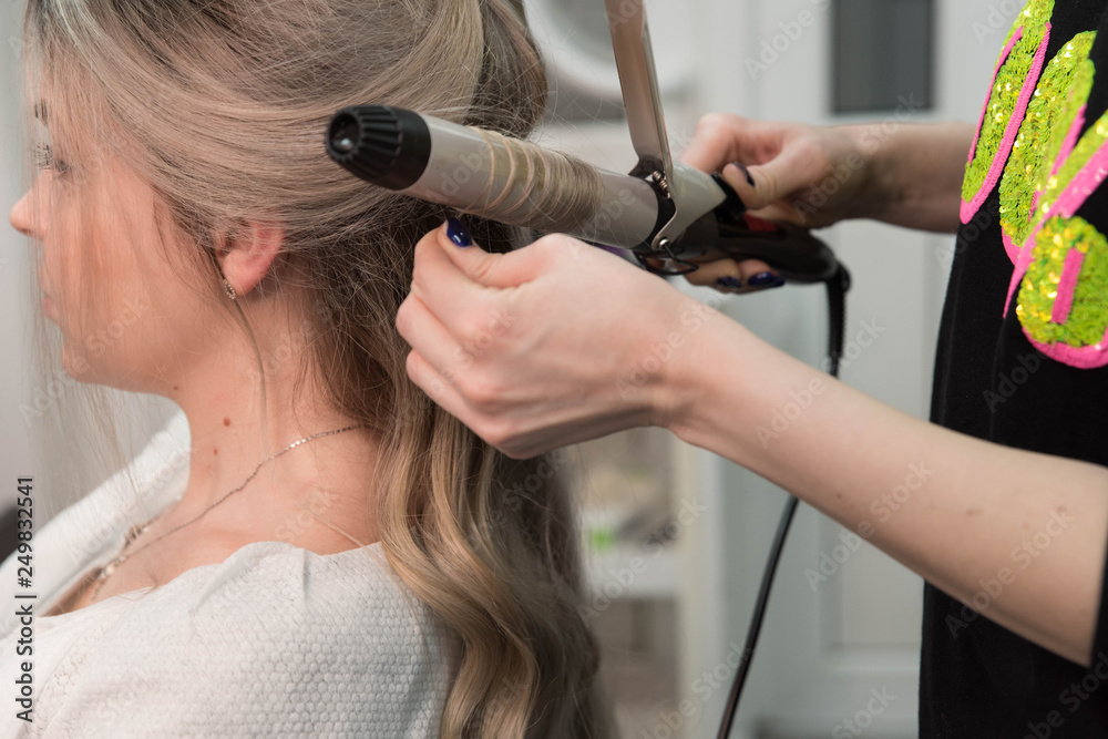Fototapeta premium Professional hairdresser makes curls using curling