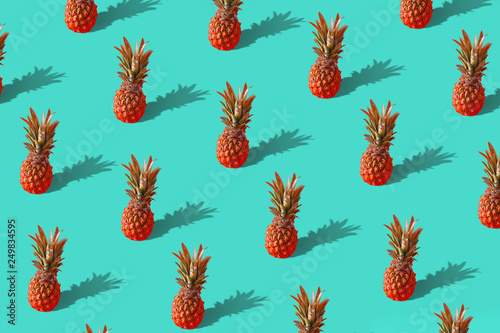 Summer colorful fruit minimal pattern of fresh red pineapples on green backgr...