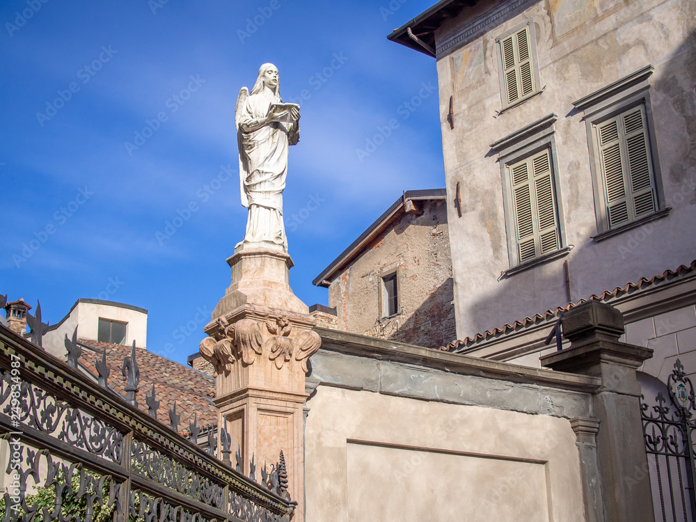 Statue of Maria with the book on the fence of Baptistery in Bergamo, Italy
