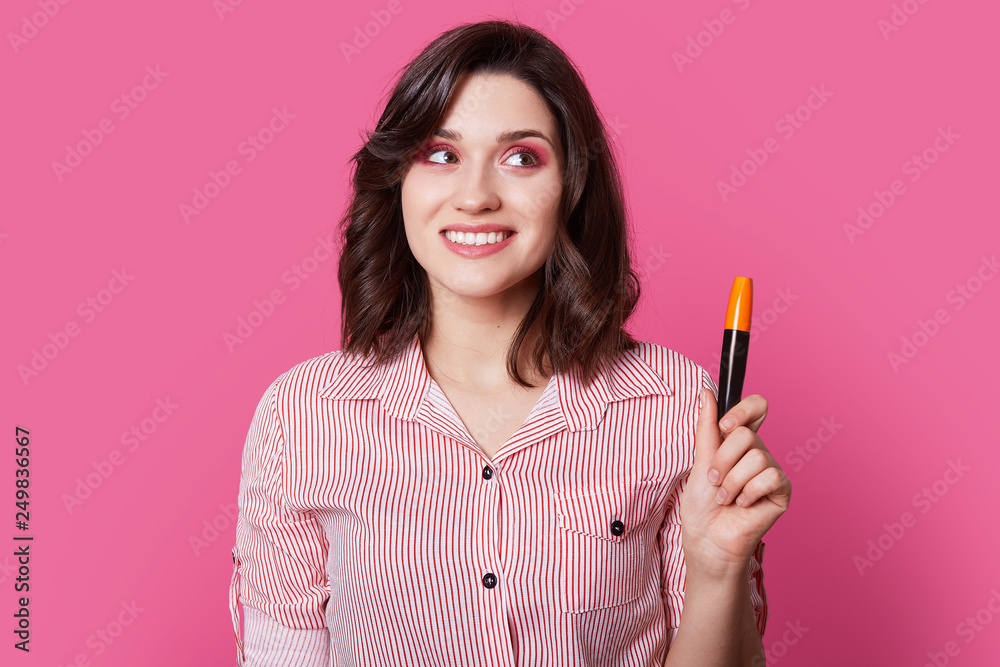 Darkeyed teen model with trendy shirt print posing on stylish isolated pink background with mascara, for her eyelashes that are located above eye. This decorative cosmetics gives confidence for lady. Darkeyed teen model with trendy shirt print posing on stylish isolated pink background with mascara, for her eyelashes that are located above eye. This decorative cosmetics gives confidence for lady.