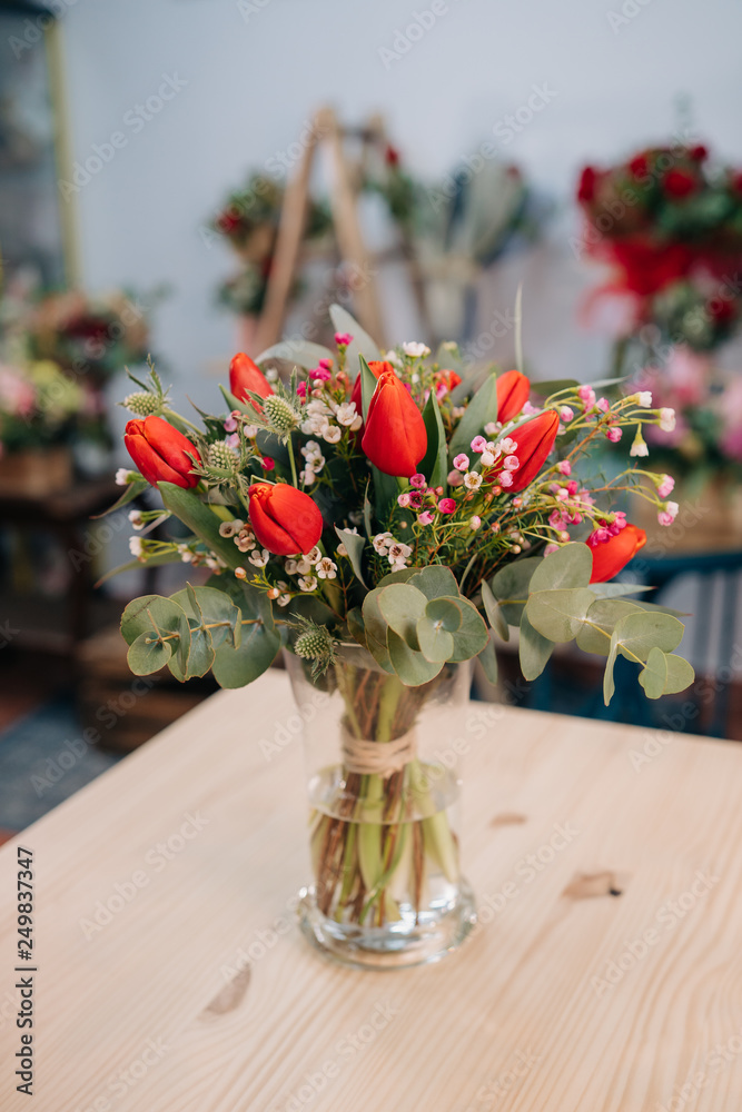 Nice red and orange tulip bouquet on a wooden table in a florist Nice red and orange tulip bouquet on a wooden table in a florist