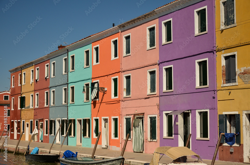 Colorful concept, orange, pink, purple. Venice, Burano island canal, small colored houses and the boats