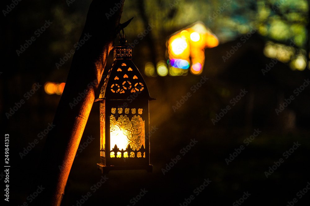 Beautiful colorful illuminated lamp in the garden in misty night. Retro style lantern at night outdoor.