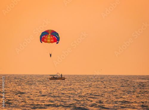 Parasailing on Baga Beach, Goa in summer. person under parachute hanging mid air. Having fun. Tropical Paradise. Positive human emotions, feelings, family, travel, vacation.