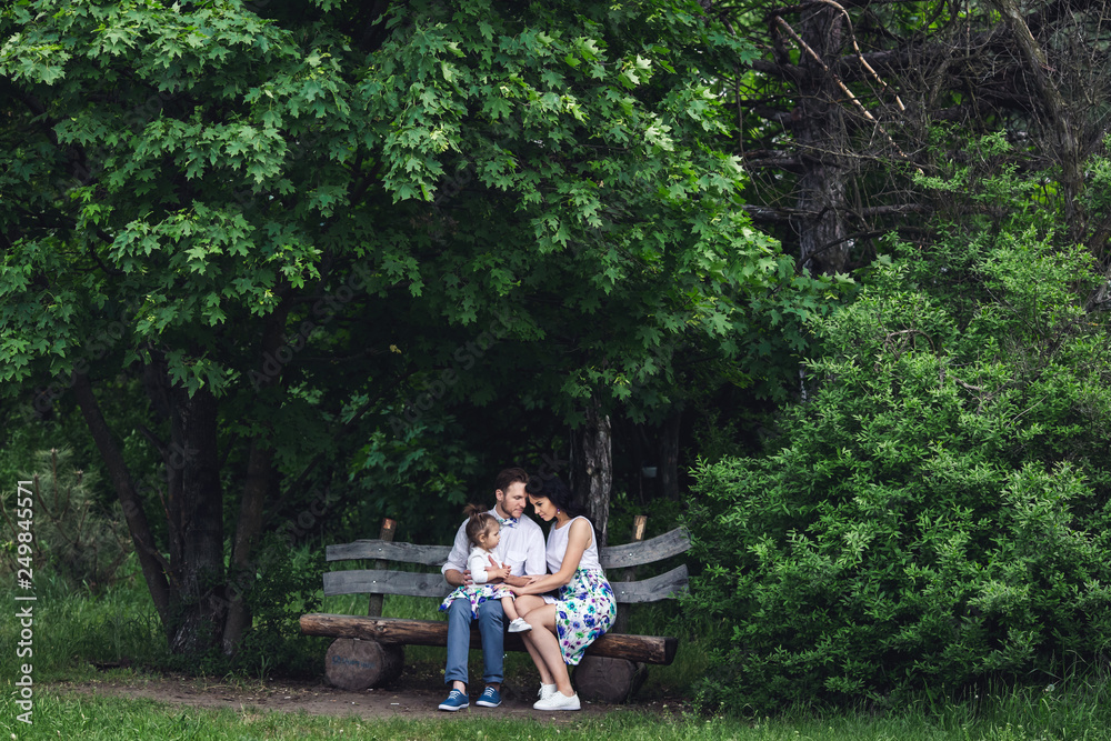 friendly happy family resting on a wooden bench under the maple friendly happy family resting on a wooden bench under the maple