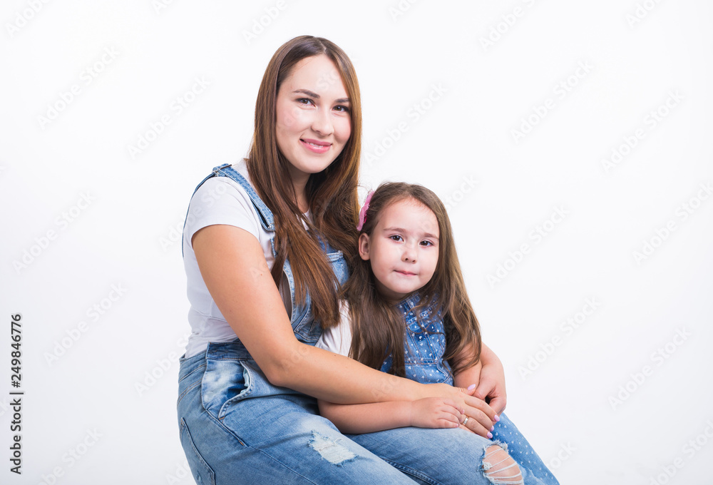 Family, children and parenthood concept - Young woman with her little cute child on white background. Mom with daughter isolated. Family, children and parenthood concept - Young woman with her little cute child on white background. Mom with daughter isolated.