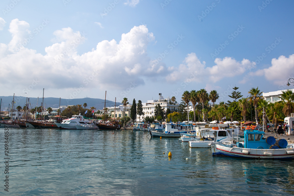 Fishing and tourist boats and and palm trees alley near Kos island coastline, Greece. 