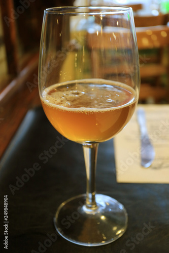 One glass of gold color chilled craft beer on a dining table