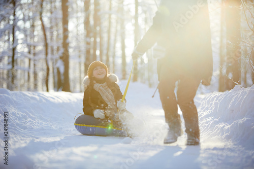 Fotografie Full length portrait of happy little girl enjoying sleigh ride in winter forest