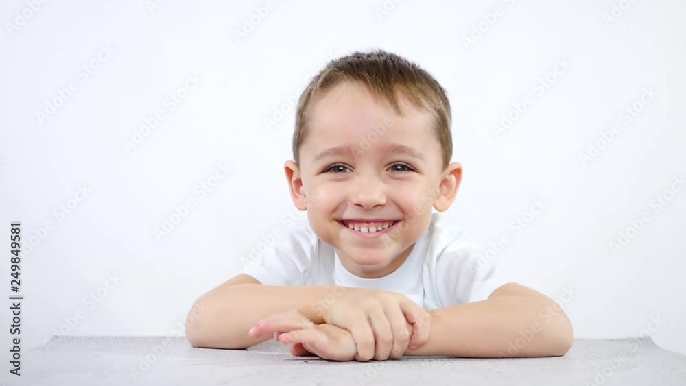 Portrait of a child sitting at the table, on a white background Portrait of a child sitting at the table, on a white background