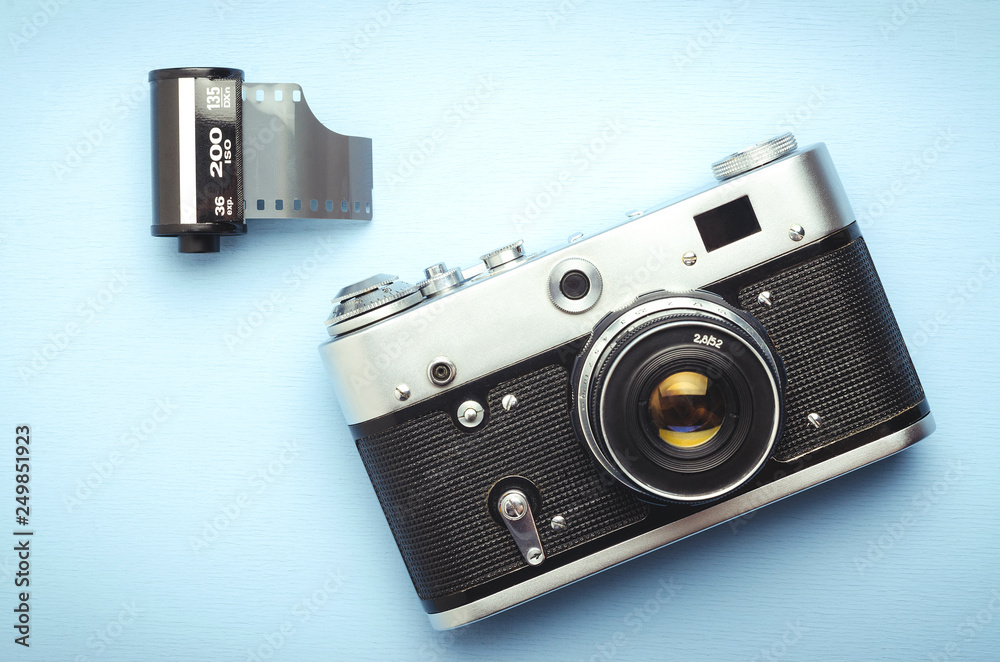 Vintage old film camera and a 35mm reel of film on a blue background, top  view Stock Photo