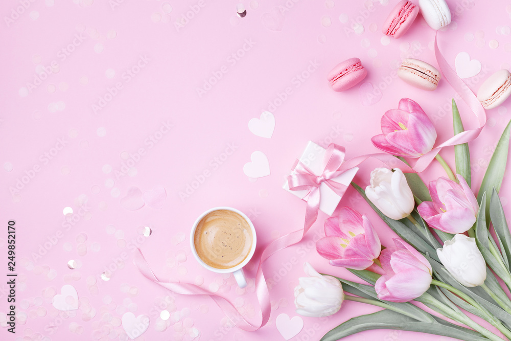 Morning cup of coffee, cake macaron, gift box and spring tulip flowers on pink background. Beautiful breakfast for Women day, Mother day. Flat lay.