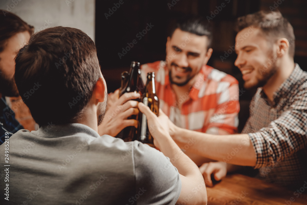 Four Jolly old friend, celebrate narrow range in Brasserie, drinking craft beer beverages from bottles, talking toast