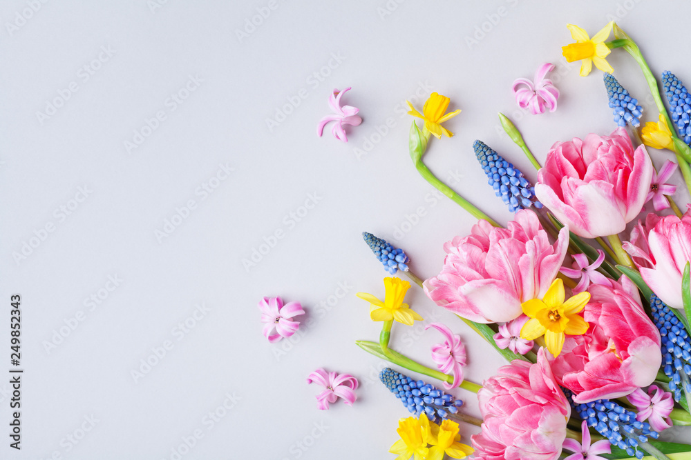 Bouquet of beautiful spring flowers on pastel table top view. Greeting card for International Women Day. Flat lay.