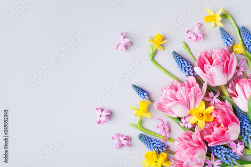 Bouquet of beautiful spring flowers on pastel table top view. Greeting card for International Women Day. Flat lay.