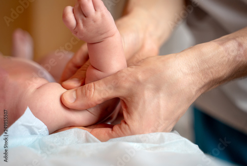 Photo of hands of masseur and baby on massage table.
