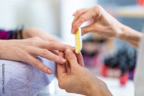 Closeup of manicurist filing finger nails