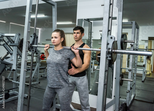 Personal instructor helping woman to lift a dumbbell