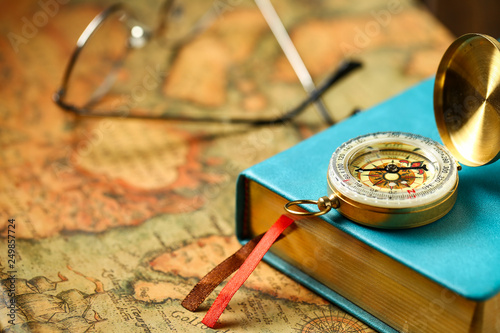 close up view of Compass and book on vintage old map background