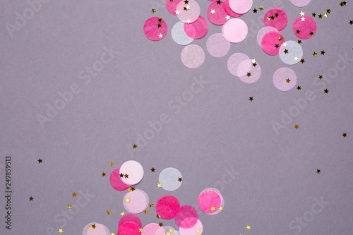 Pink confetti with gold stars on gray background with copyspace