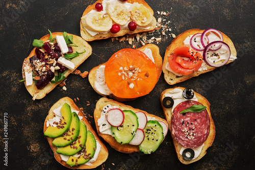 A variety of vegan sandwiches with vegetables and fruits on a dark rustic background. Top view, flat lay. The concept of healthy eating.