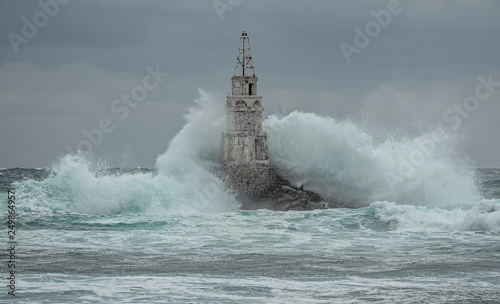 Lighthouse and storm in the sea and large waves that break into the sea light at the port of Ahtopol, Black Sea, Bulgaria