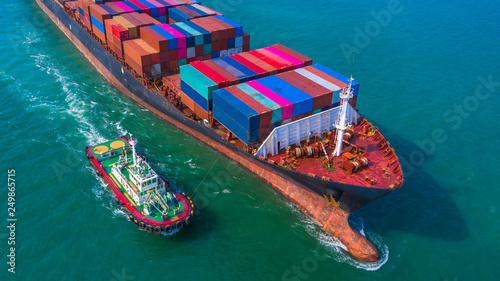 Container ship arriving in port, Tug boat and container ship going to deep sea port, logistic business import export shipping and transportation, Aerial view.